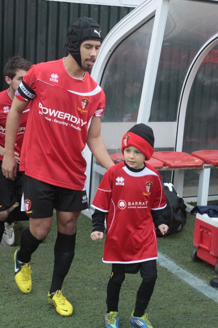 Mascot Remy Bashir and skipper Sam Cox lead out United